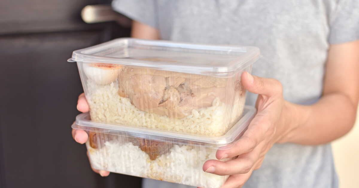 Une personne tenant des aliments dans des boîtes en plastique